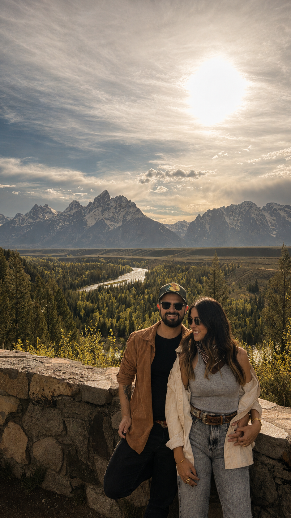 Casal sentado em uma cerca de madeira diante das montanhas Grand Teton